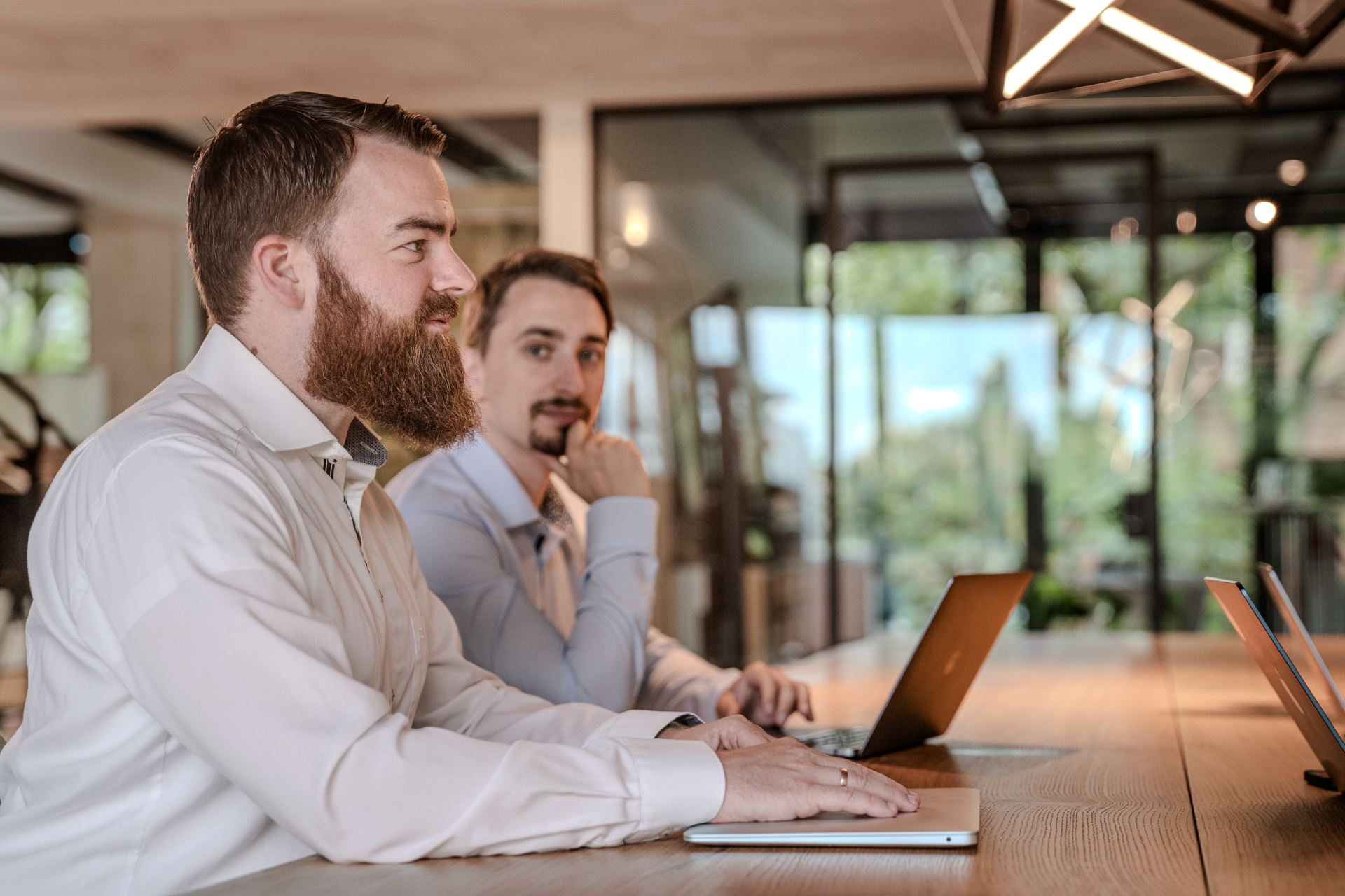 "Two professionals engaged in an AI Discovery Workshop session, seated with laptops in a modern office setting, collaboratively exploring strategic applications of artificial intelligence for business growth."
